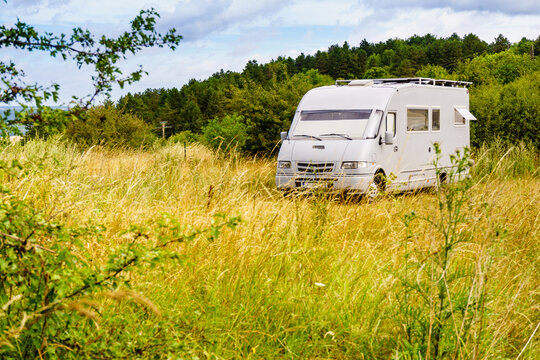 Camping car parked in a field with blue sky during daytime in a rural area