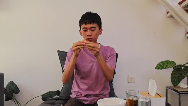 Young man inspecting and splitting fried dumpling pieces prior to eating batagor