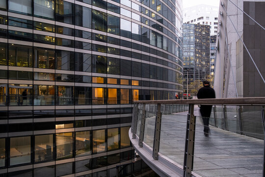Pedestrian on an elevated walkway in La Defense Paris France surrounded by office buildings and modern urban architecture at dusk scene