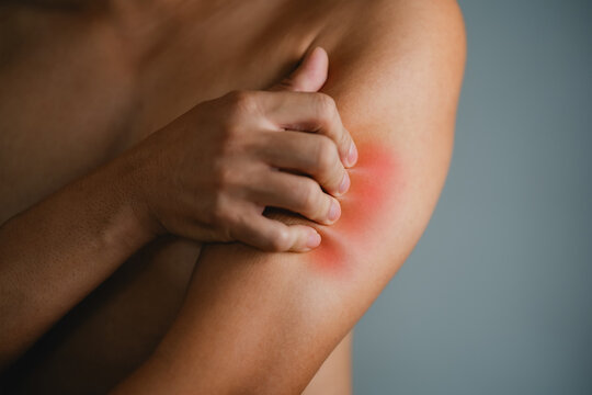 Man with bruise on shoulder against grey background, closeup 

