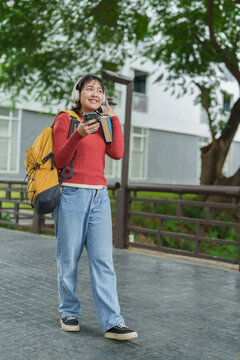 Female student walking on campus listening music