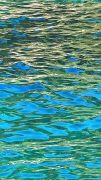 Turquoise sea water shimmering in sunlight near Croatian coast. Moving ripples and reflections create abstract natural background