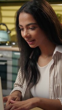 Thoughtful Latina Arabian Indian woman thinking typing laptop in kitchen home student freelancer think plan idea solution working happy pointing finger online studying shopping computer looking screen