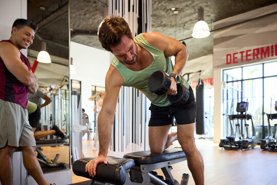 Man lifting dumbbells in gym. He's focused and determined, pushing through the weight with grit. Sweat and effort. Dumbbell Row. Office in-house gym