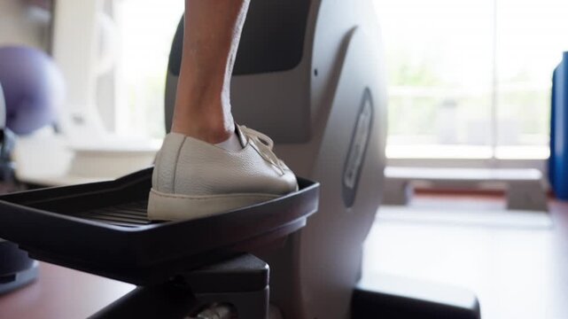 Personne &acirc;g&eacute;e s'entra&icirc;nant sur un v&eacute;lo elliptique en salle de sport