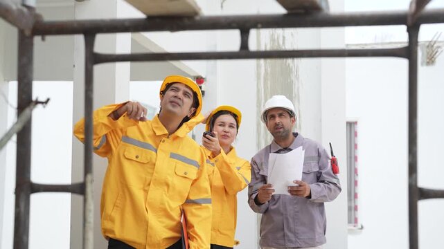 Civil engineer and construction workers look upward while discussing building work during site inspection, checking structure, progress, safety, project development.