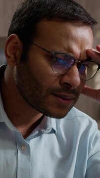 Angry frustrated Indian American business man throwing papers desk stressed worker with laptop tired unhappy male businessman office employee deadline paperwork problem burnout hate trouble hard work
