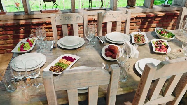 A long wooden table in a winery restaurant is laid with plates of Georgian salads, pkhali, bread and rows of wine glasses.