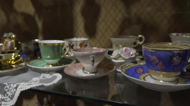 Row of colorful vintage porcelain teacups and saucers in green pink and blue displayed together in an antique shop