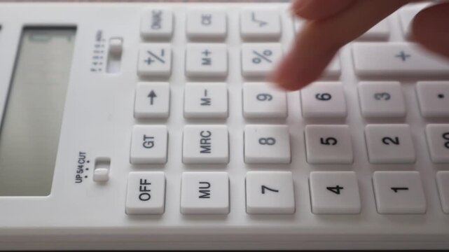 白い電卓で計算している女性の手元のアップ