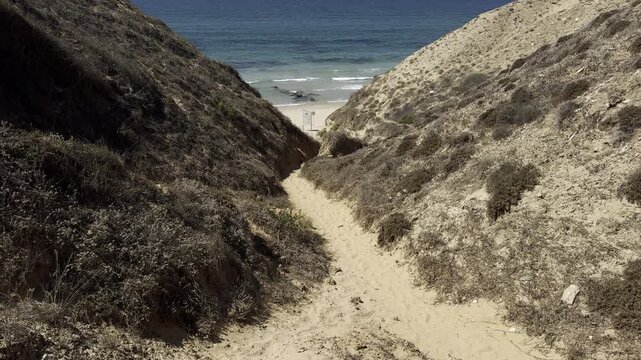 Netanya, Israel. View through rocky formations of Jerusalem limestone across a narrow gorge toward a sandy beach along the Mediterranean coast.