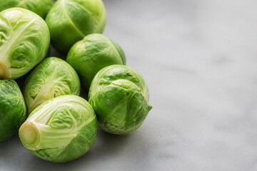 Fototapeta premium Brussels sprouts are displayed on a light gray surface against a blurred background.
