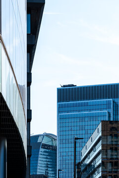 Street level view toward modern office towers in The City of London England framed by reflective buildings and a narrow urban corridor