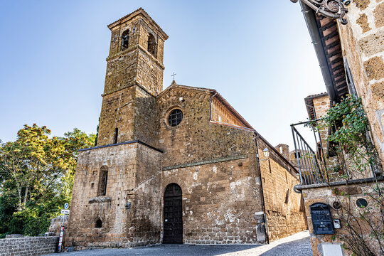 Austere stone facade of the Church of San Giovenale, built in 1004 over the remains of an early Christian church and flanked by its medieval bell tower, Orvieto, Umbria, Italy