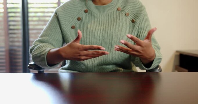 Close up of people talking to the camera, gesturing with hands, woman in green sweater sitting at ta