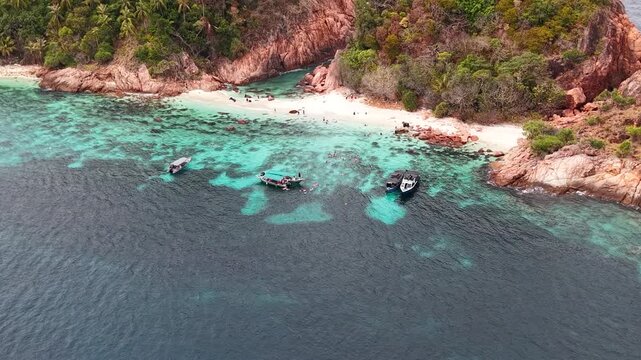 Aerial view of boats at a tropical beach paradise with clear turquoise water and snorkelling people