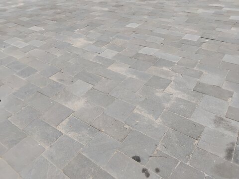 A wide perspective view of grey stone tiles arranged on outdoor pavement