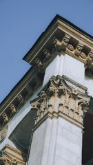 Low angle view of classical architecture column with Corinthian capital and ornate cornice against blue sky © Вита Курило