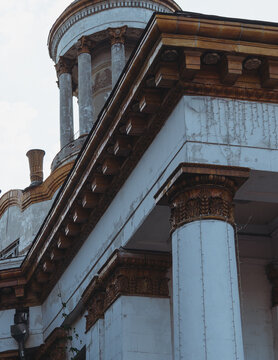 Low angle view of historic monumental neoclassical building with columns, round rotunda tower, and decorative glazed ceramic cornice details.