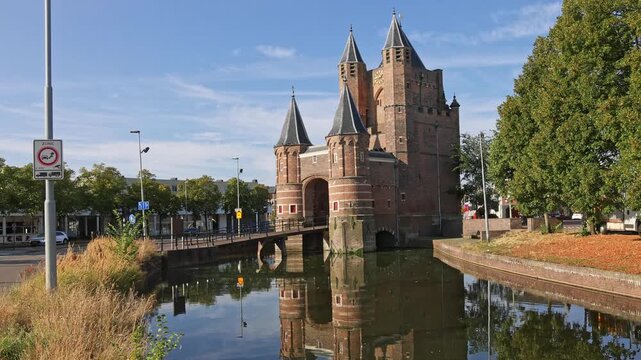 Full view of the medieval Amsterdamse Poort city gate reflected in calm canal water on a clear sunny day in Haarlem, Netherlands on 16 August 2026.
