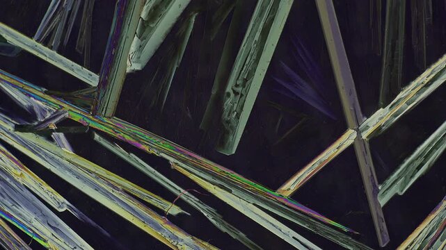Birefringent Epsom salt crystals under polarized light microscopy showing vibrant color transition and interference changes with shifting polariser filter angle for scientific background