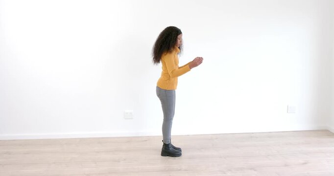 Stretching on wooden floor, African American woman in yellow sweater focusing on flexibility