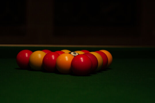 Low-angle close-up of red and yellow English pool balls racked in a triangle on green felt