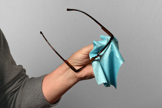 main qui nettoie les lunettes sur fond gris