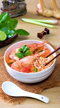 Instant noodles, Tom Yum Goong spicy shrimp soup In a white bowl. on a wooden table