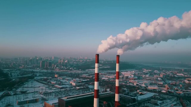 Close-up of two industrial smokestacks in the city emitting smoke and polluting the atmosphere.