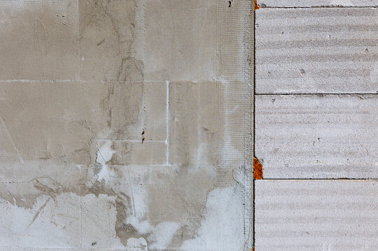 Comparison of aerated concrete block wall construction, with adhesive mortar and fiberglass reinforcing mesh applied on the left while bare masonry blocks remain exposed on the right.