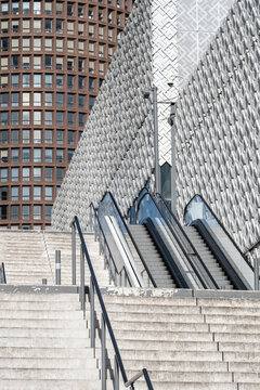 Wide staircase with metal handrails leading toward contemporary buildings creating strong architectural lines and perspective in a modern urban public space