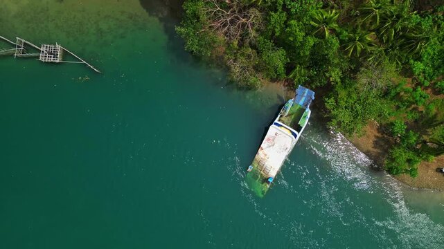 Abandoned boat resting near the coastline of Cagraray Island close to Sula Bridge, captured from above with tropical vegetation, coastal waters and the surrounding island landscape.