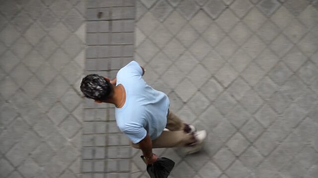 Persona con smartphone y perspectiva a&eacute;rea tel&eacute;fono app pantalla latino usando celular m&oacute;vil sudamericano caminando 