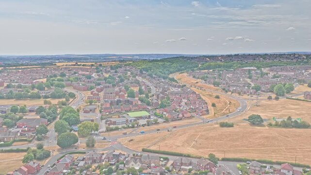 Greasbrough shows residential streets, B6089 Car Hill and dry arable fields around the urban edge of Rotherham, South Yorkshire, England, drone ascent