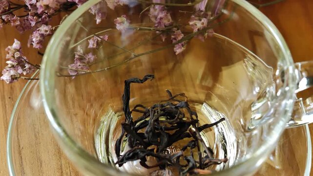 Dried  tea leaves in a clear glass cup on a wooden table