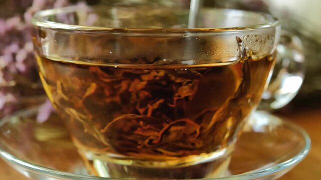 Hot tea in a clear glass cup on a wooden table