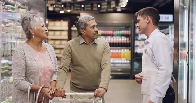 Old couple, grocery shopping and help with employee, question and search for diet options in store. Mature man, woman and customer in supermarket with fridge aisle for wellness, health and nutrition