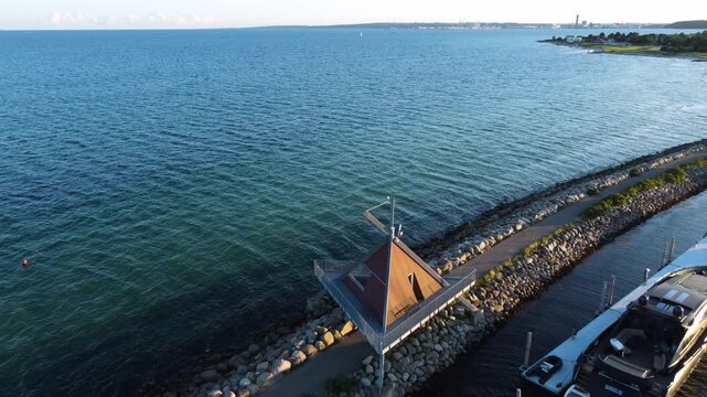 Calm sea and long breakwater beside Ega Marina near Aarhus, Denmark at evening, aerial