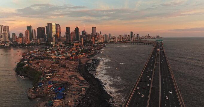 4k aerial view of Mumbai Sea link during orange blue sunset in Monsoon. Beautiful golden hour view of the Mumbai slum and Arabian sea with cars running on the bridge. Cityscape of skyscrapers