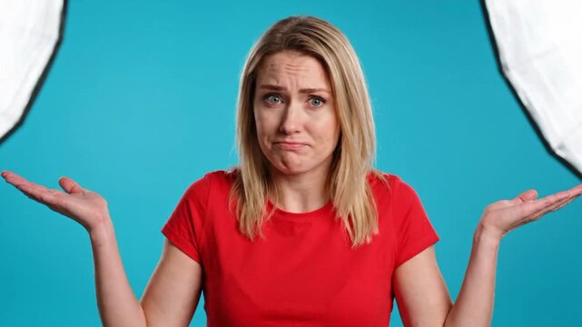 Clueless woman portrait with whatever gesture in front of blue background
