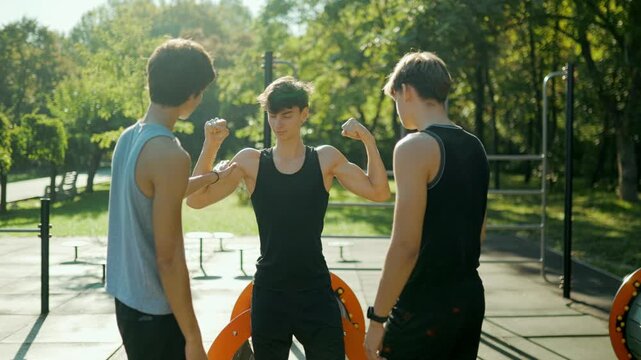 Generation Z boys showing off arm muscles during an outdoor team workout.