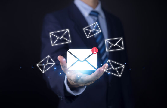 Businessman holding glowing email icon with floating messages, symbolizing digital communications, email marketing, customer engagement, online messaging, corporate technology, and connectivity today.