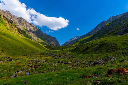 Vibrant Green Mountain Valley with Stream and Blue Sky
