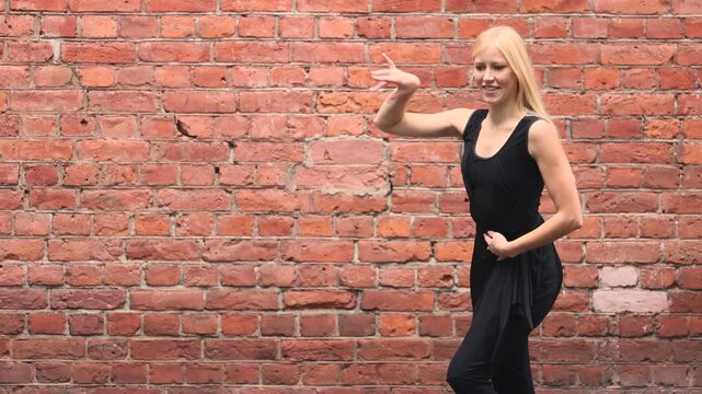 Ballroom dancer moves through Latin steps against brick wall