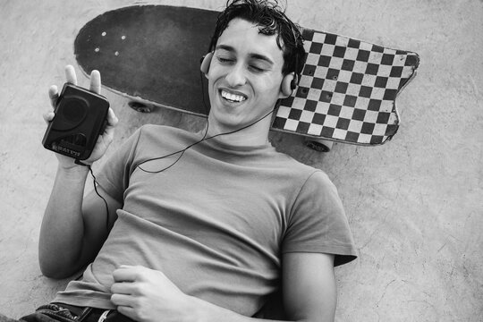 Young man listening music with cassette player - New trend people lifestyle using vintage analog device - UGC content - Focus on face - Black and white film camera editing