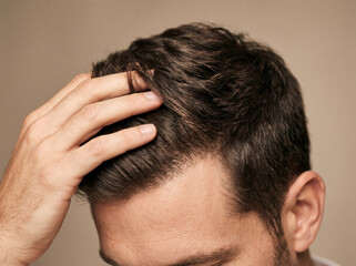 Close-up of a man's hand running through thick dark hair, illustrating healthy growth and successful hair restoration treatment. © Tania Zbrodko