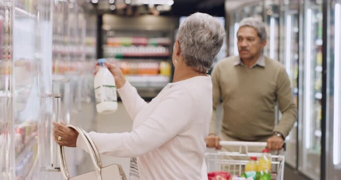 Old woman, shopping and fridge at store for groceries, milk and brand comparison with partner. Senior couple, consumer and trolley in supermarket with ingredients, dairy product and food essentials