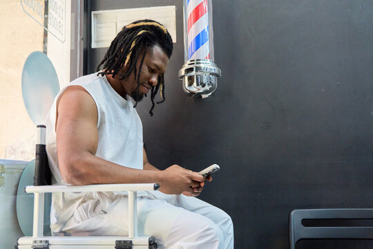 Black man communicating using smartphone in barbershop