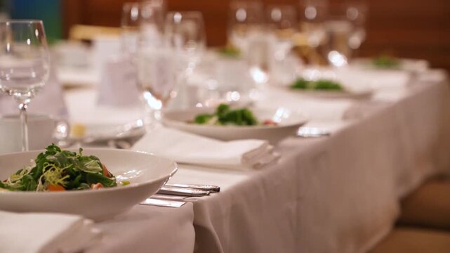 Cinematic footage of an elegant banquet table setting with crystal glassware, silverware, and a microphone, perfect for formal events and weddings.
